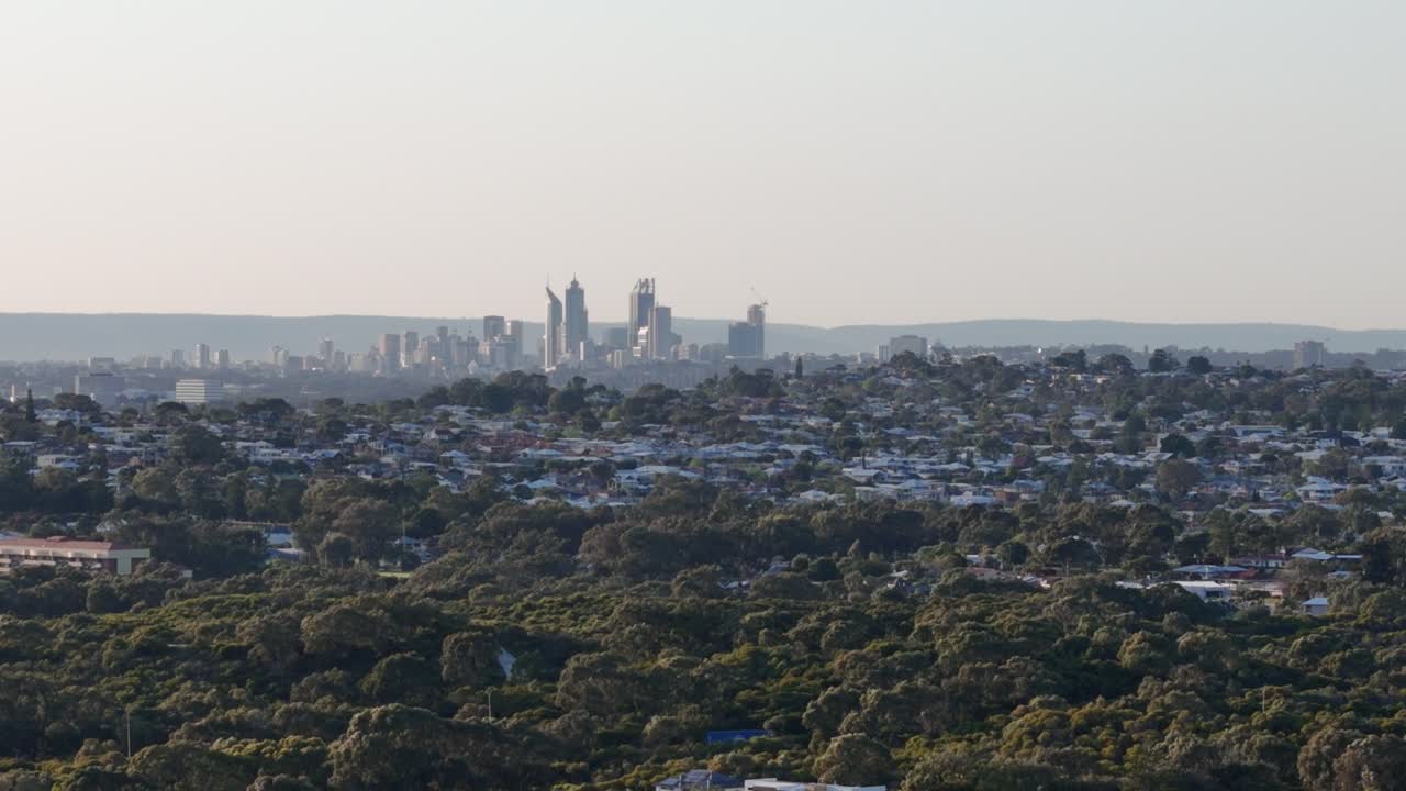 서 오스트레일리아의 언덕 위에 빛이 뜨는 해가 뜨는 동안 퍼스 시의 스카이라인을 둘러싼 드론