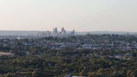 Drohne-Schwenkt-Bei-Sonnenaufgang-Um-Die-Skyline-Von-Perth,-Während-Das-Licht-über-Den-Hügeln-Westaustraliens-Aufsteigt