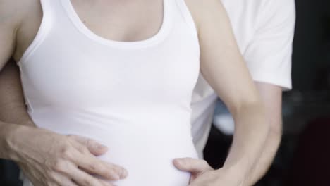 front view of cheerful couple talking and touching belly