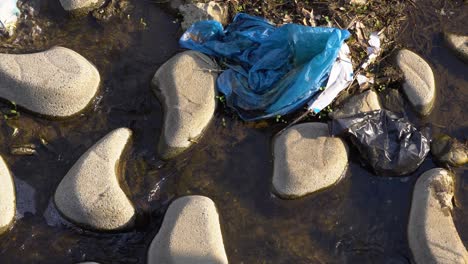 plastic waste on rocks of an urban river at yangjaecheon stream in seoul, south korea