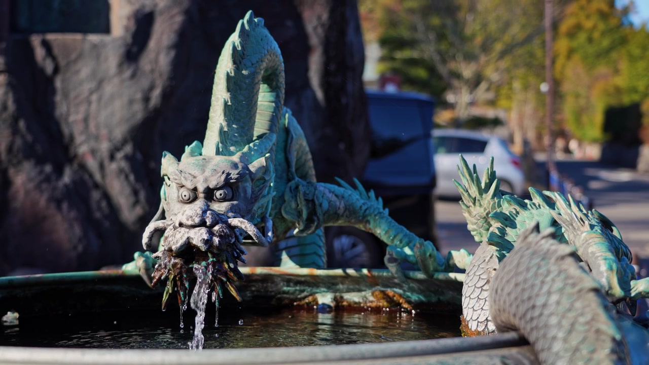 Close-up of an ornate Japanese dragon fountain pouring flowing water into a stone basin, showcasing traditional Asian design, mythology and cultural symbolism in Japan.