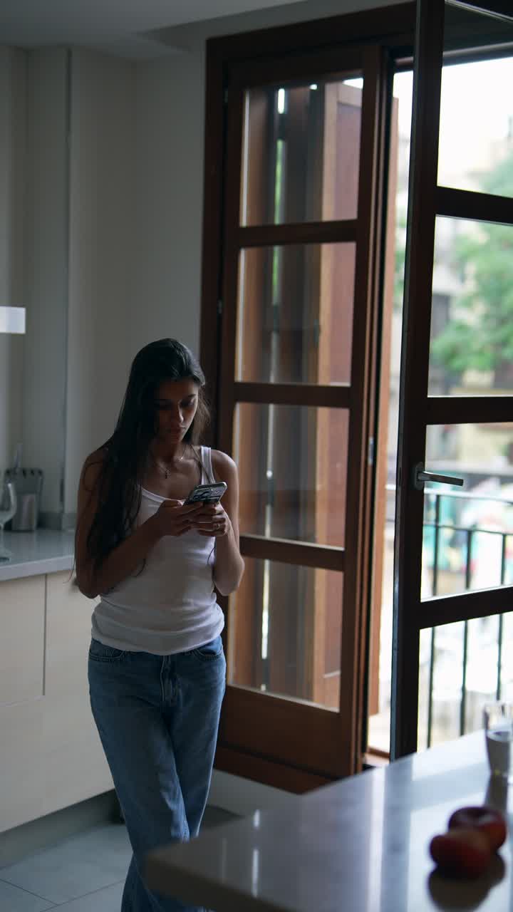 mujer usando teléfono móvil en una cocina