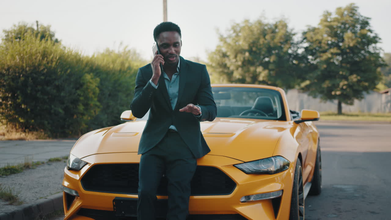 hombre de negocios en el teléfono por coche descapotable amarillo