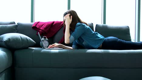 mujer asiática atractiva disfruta de un tiempo de relajación con una computadora portátil en la sala de estar fondo de la casa