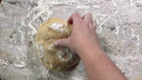 overhead view of hands rolling out dough into thin round