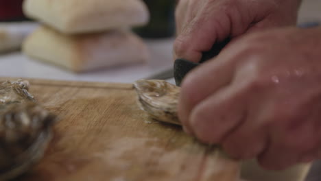 hands shucking oyster with knife