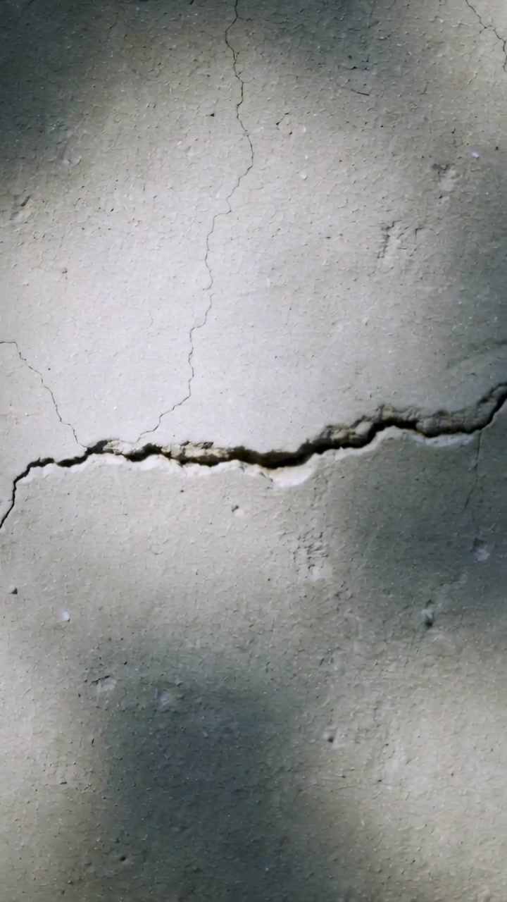 Vertical video: Filming hand cam documenting concrete crack across slab while sunlight shifting