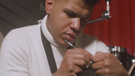 close up view of a latin man sitting in the recording studio and writing in the notebook