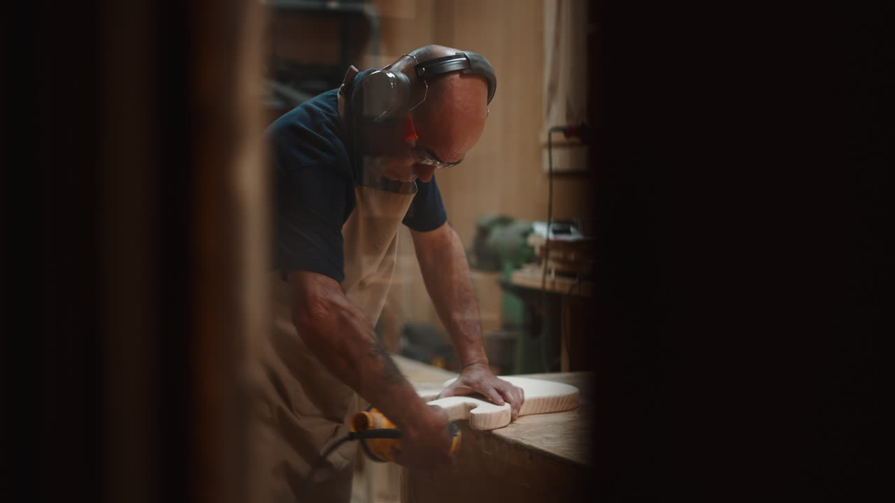 Skilled Craftsman Sanding a Wooden Guitar Body in a Workshop