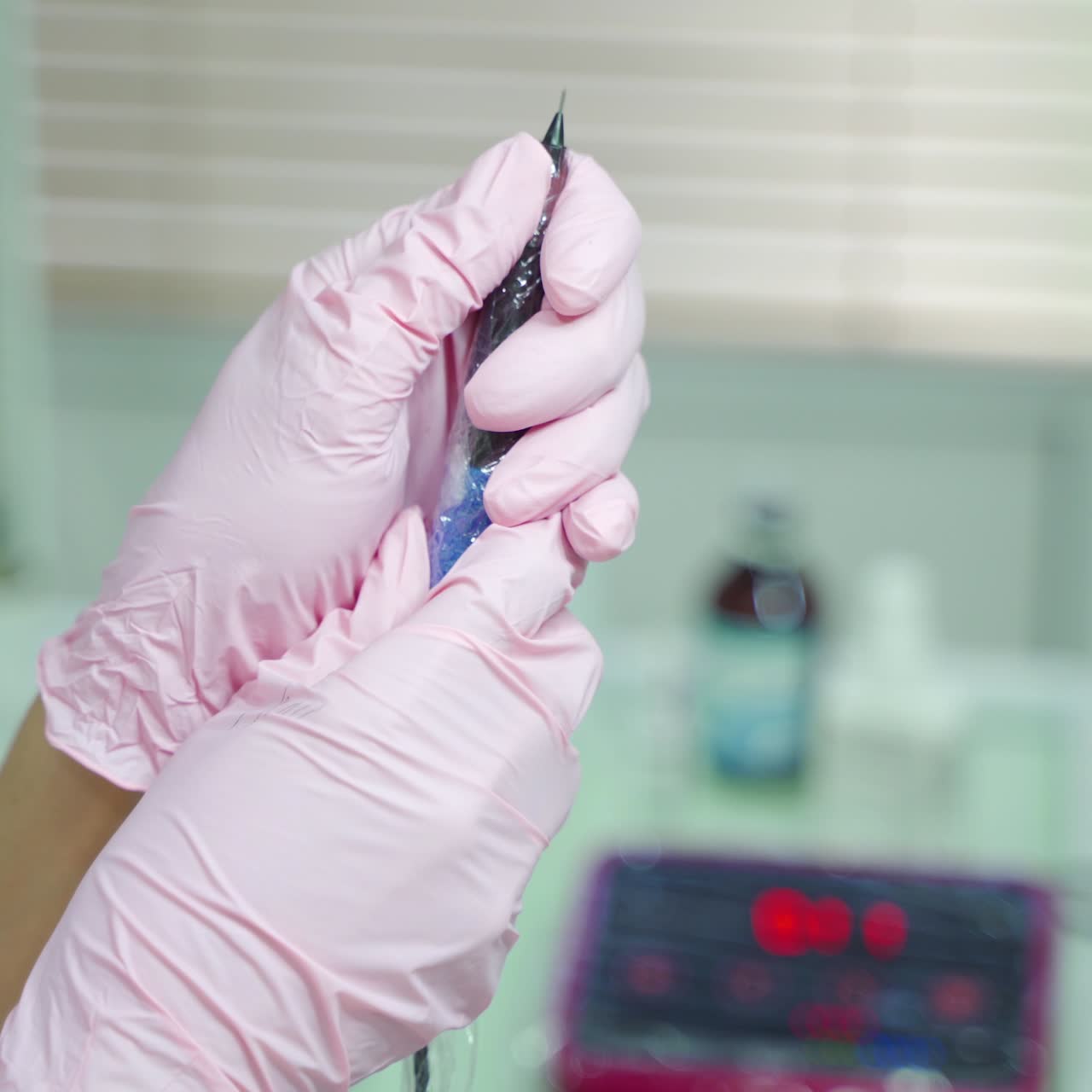 beautician is holding in her hands professional cosmetic tool for permanent makeup of eye. Needle for using in the procedure permanent makeup