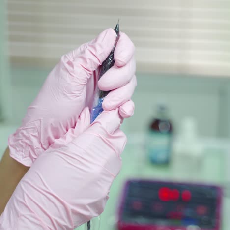 beautician is holding in her hands professional cosmetic tool for permanent makeup of eye. needle for using in the procedure permanent makeup