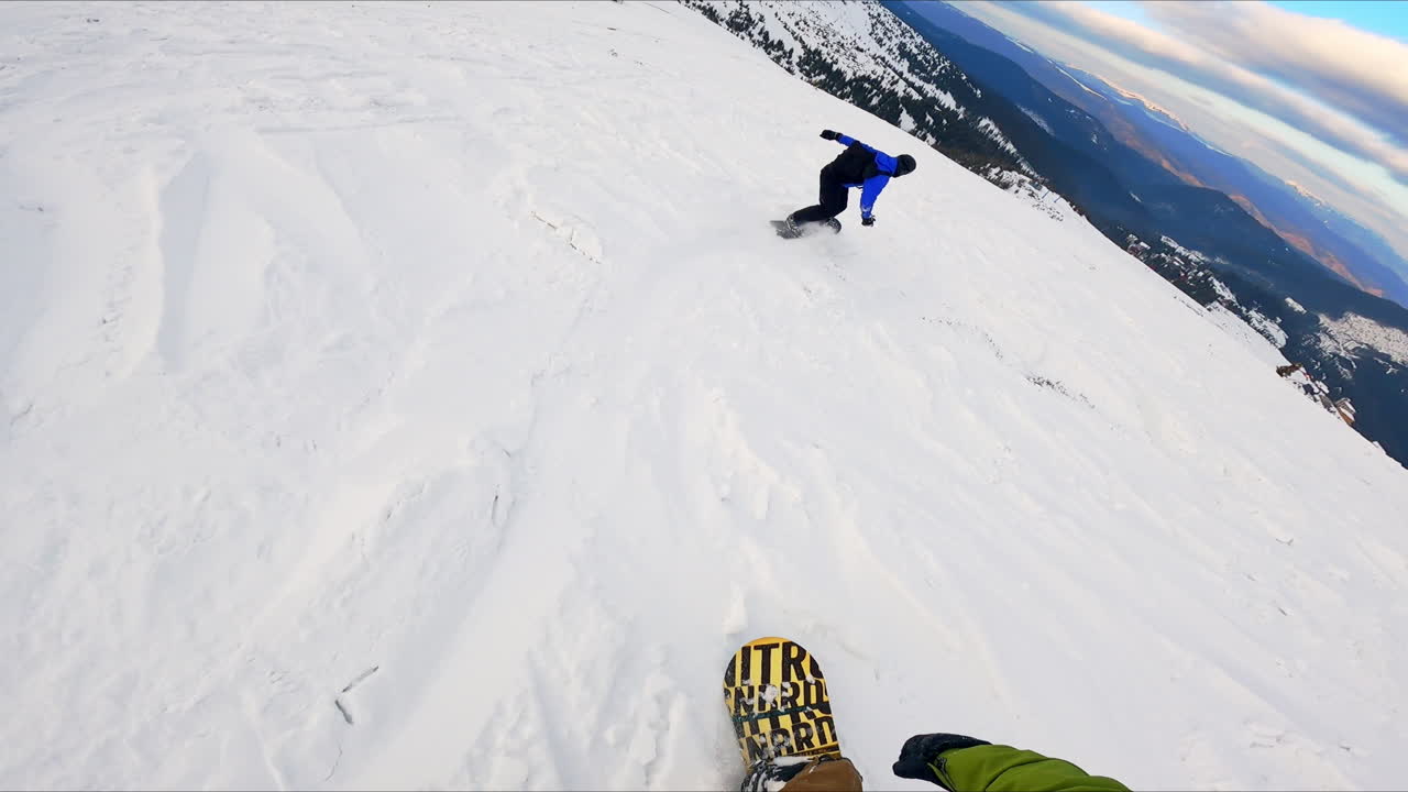 Snowboarding in the beautiful mountains. First person's video of sportsman riding by the snowy slope.