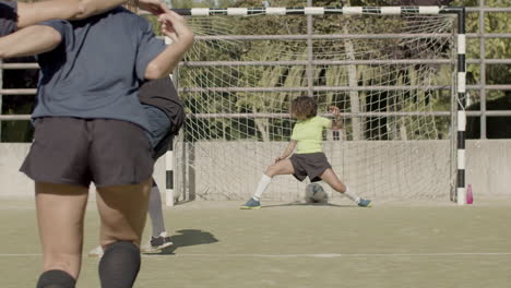 vista trasera de una jugadora de fútbol pateando un penalti y marcando un gol