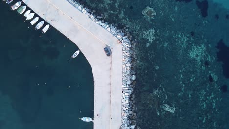 top view shot of a sea wall seperating the open sea and protecting the marina | multiple shades of deep blue sea | 4k