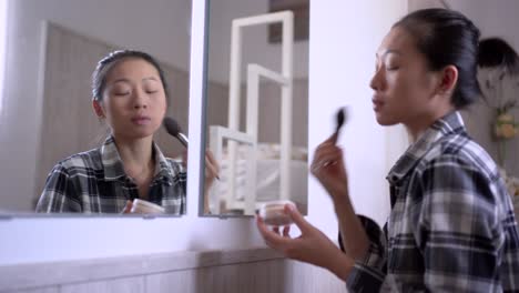 young woman applying makeup against mirror