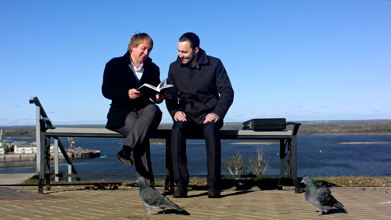 두 명의 행복한 남자가 웃으며 책을 읽고 있습니다.