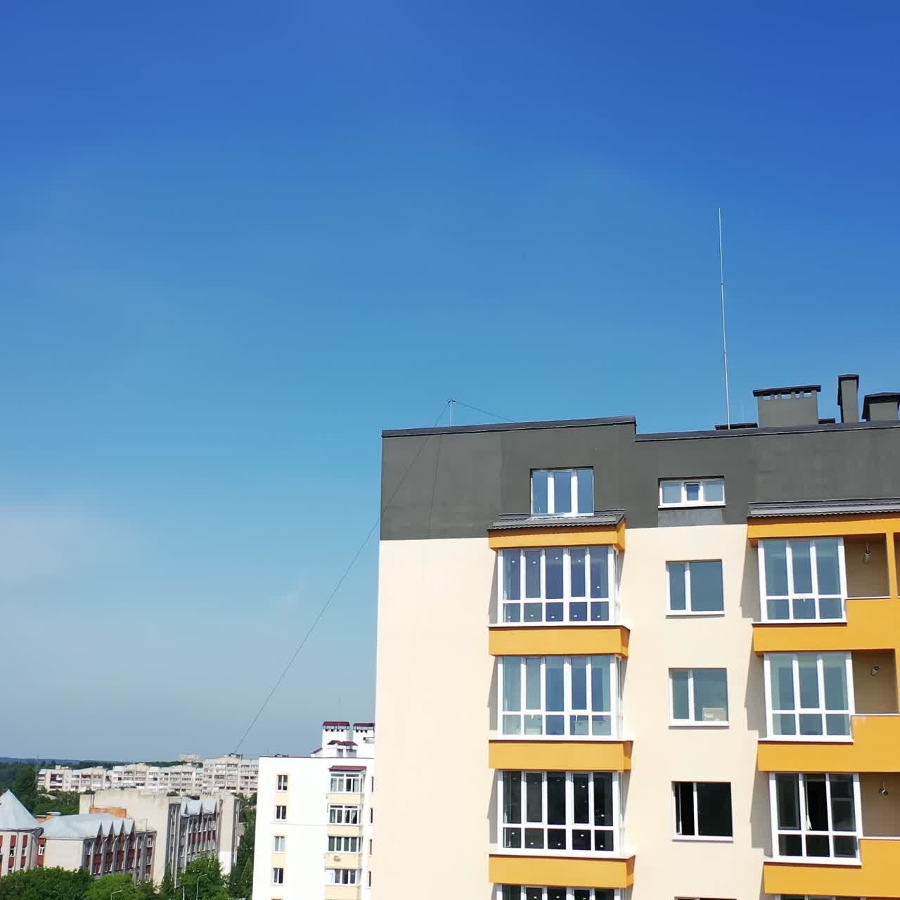 New multi-storey building in the city. Contemporary apartment building with large windows and colorful walls of the facade of a new house for city residents on sky background