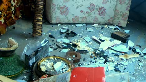 cosas rotas al azar esparcidas por un piso de cemento dentro de una casa
