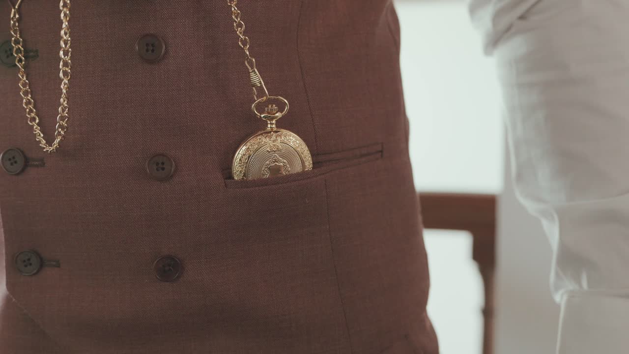 Closeup of ornate gold pocket watch tucked into tailored suit