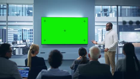 modern product presentation event: black businessman speaks, uses green chroma key screen wall tv. press conference for group of diverse multi-ethnic investors, digital entrepreneurs, businesspeople