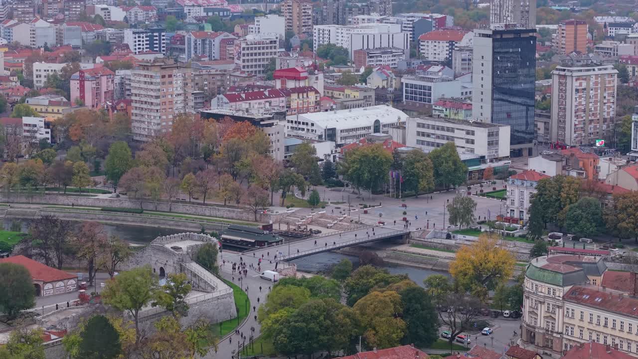 Aérea filmagem com drone sobre Niš captura o portão da fortaleza e a ponte do rio Nišava, revelando gradualmente os edifícios da cidade circundante e a paisagem urbana em uma visão cinematográfica