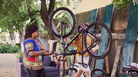 couple fixing bicycle chain with laptop