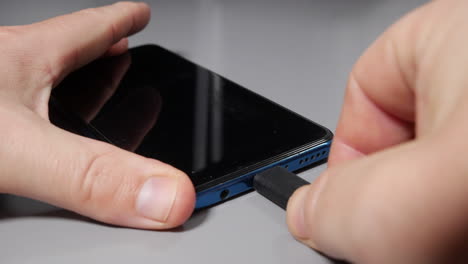 hand plugging the charger into mobile cell phone