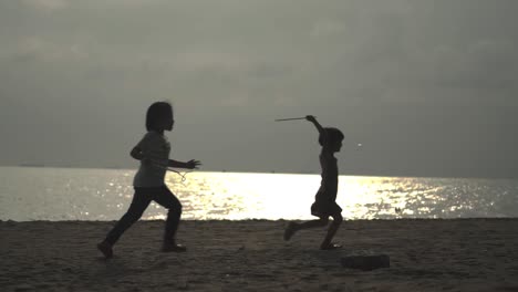 silhouette of children playing and chasing bubbles at the beach on sunset