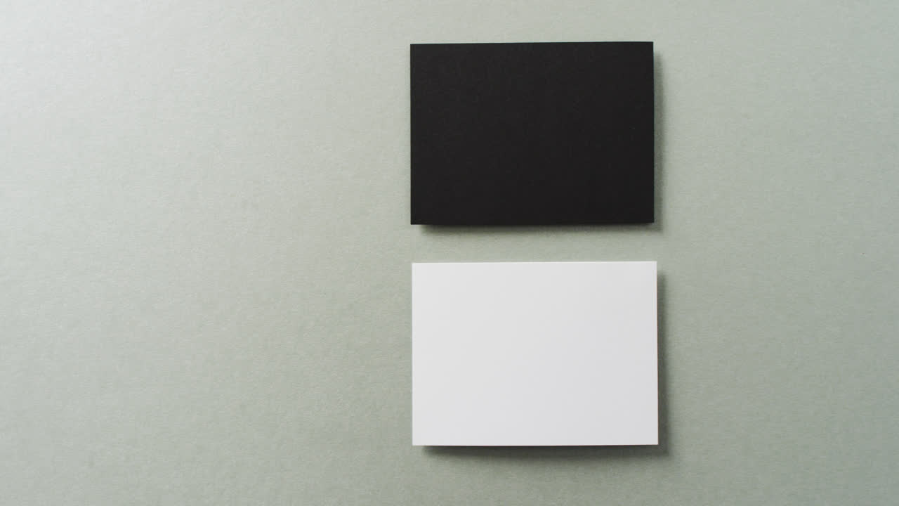 acercamiento de dos pilas de tarjetas de visita en blanco y negro sobre fondo gris, espacio de copia, cámara lenta