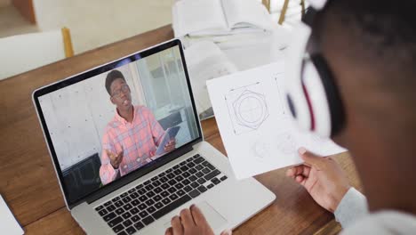 Afroamerikanischer-Männlicher-College-Student,-Der-Notizen-Hält,-Während-Er-Zu-Hause-Einen-Videoanruf-Auf-Dem-Laptop-Führt