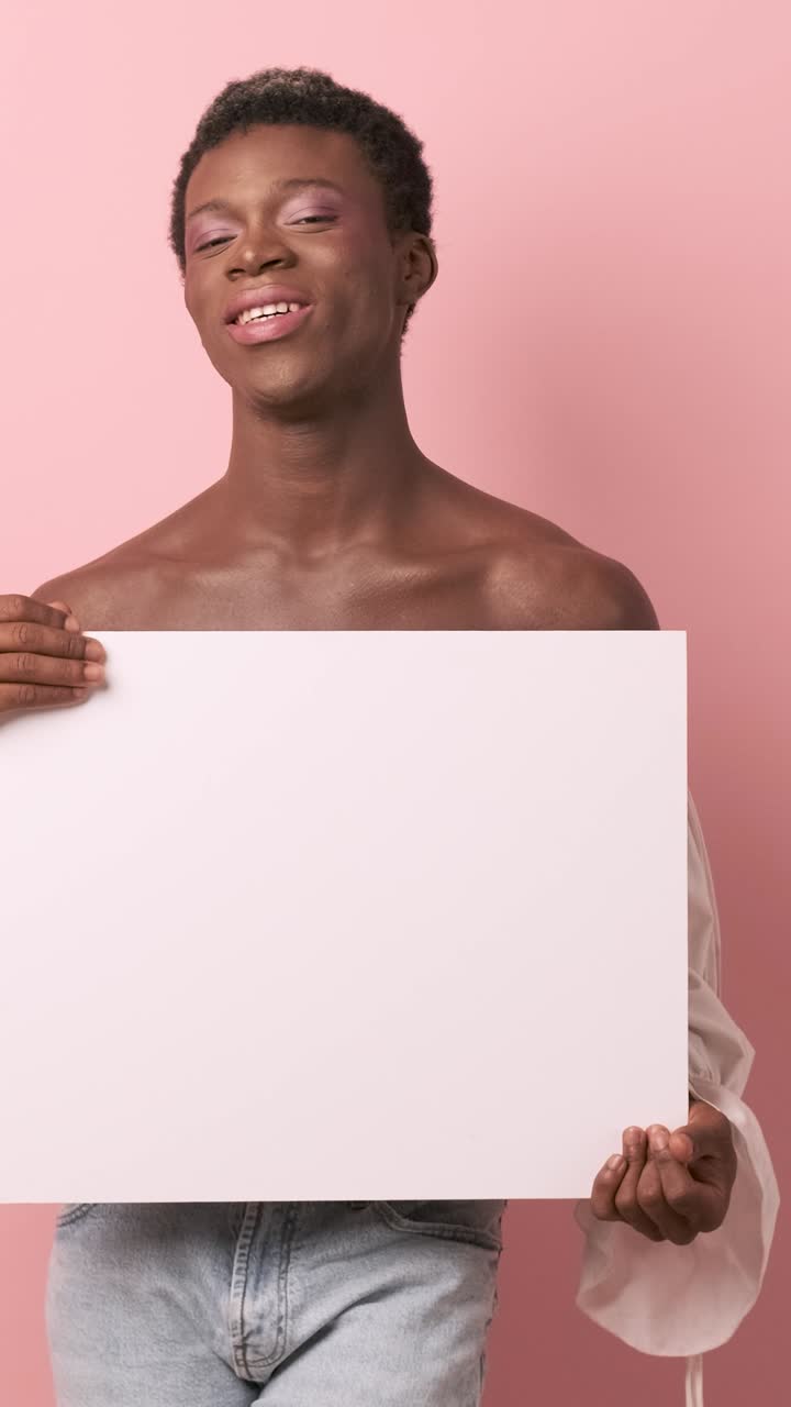 Persona transgender africana che sorride mentre tiene in mano un poster bianco vuoto