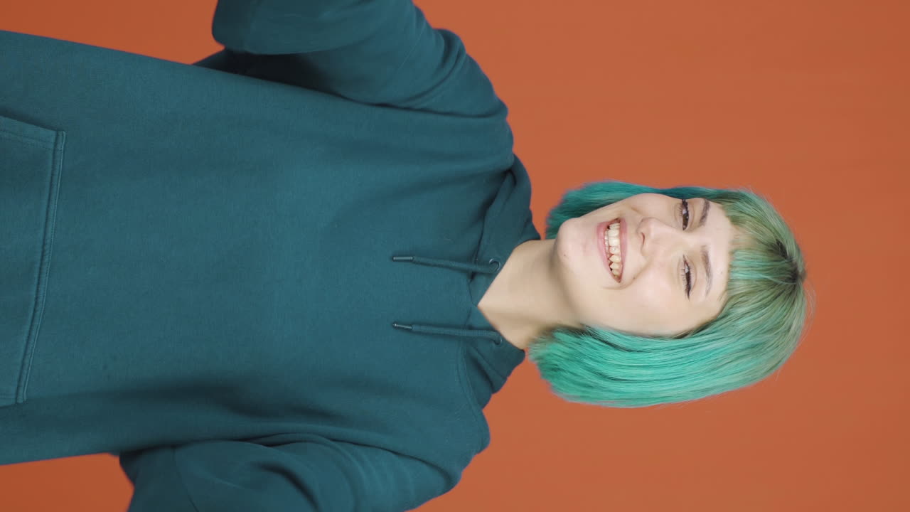 카메라를 향해 손을 흔드는 행복한 젊은 여성의 수직 비디오.