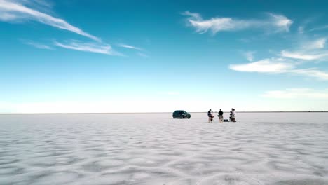 cinemática en órbita alrededor de un equipo filmando una entrevista en un área remota salinas de bonnesville, utah, estados unidos, auto negro, cielo azul y nubes