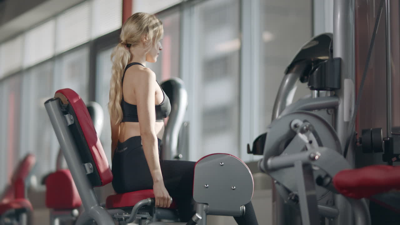 Fit woman doing fitness exercise on sport simulator in modern fitness gym.