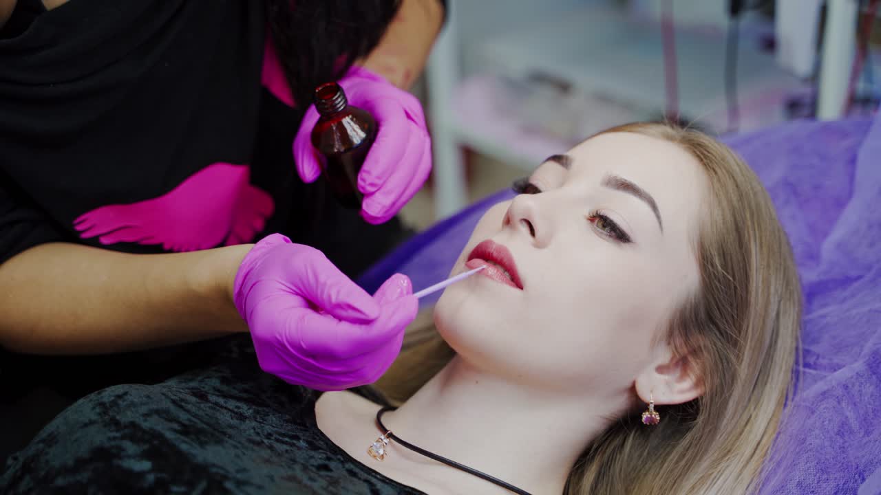 Cosmetology procedure on lips at spa salon. Master does permanent makeup on lips to a beautiful female client. Plastic medicine and cosmetology.