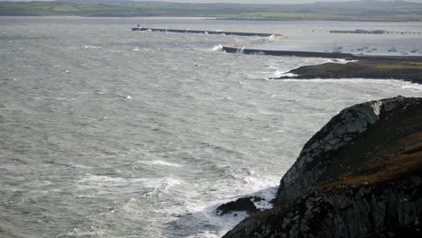 dramatic coastal scene with rough waves crashing against cliffs and breakwater