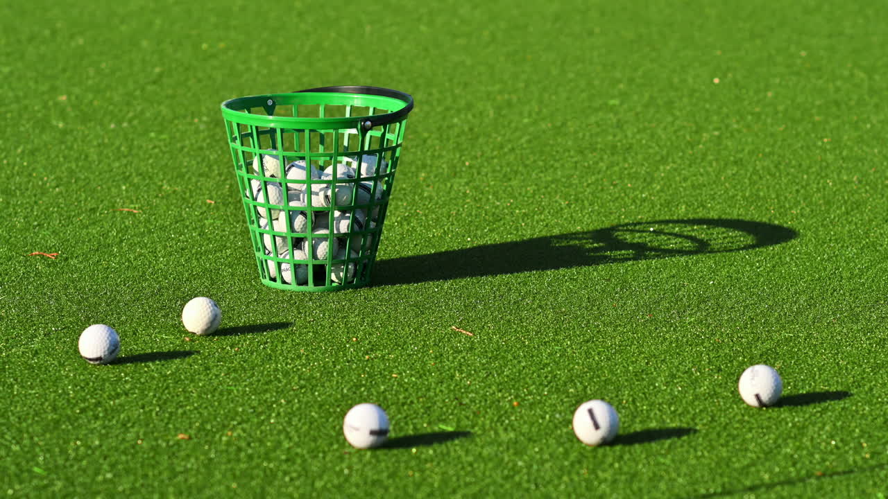 Green bucket filled with golf balls on a course, on a sunny day