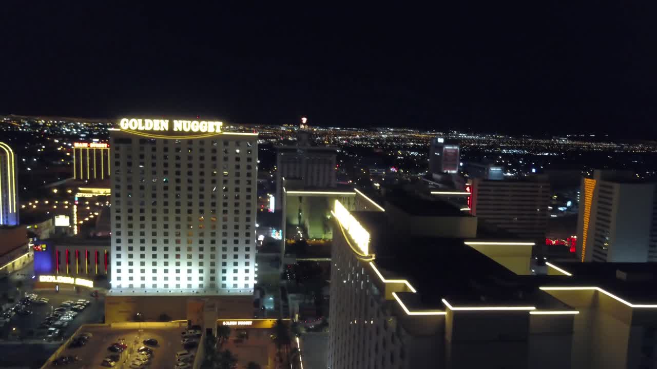 4K AERIAL: Dynamic aerial shot over the Golden Nugget Hotel and Casino in Las Vegas with the city lights in background at dusk