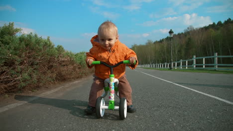 smiling toddler riding on bike in the park