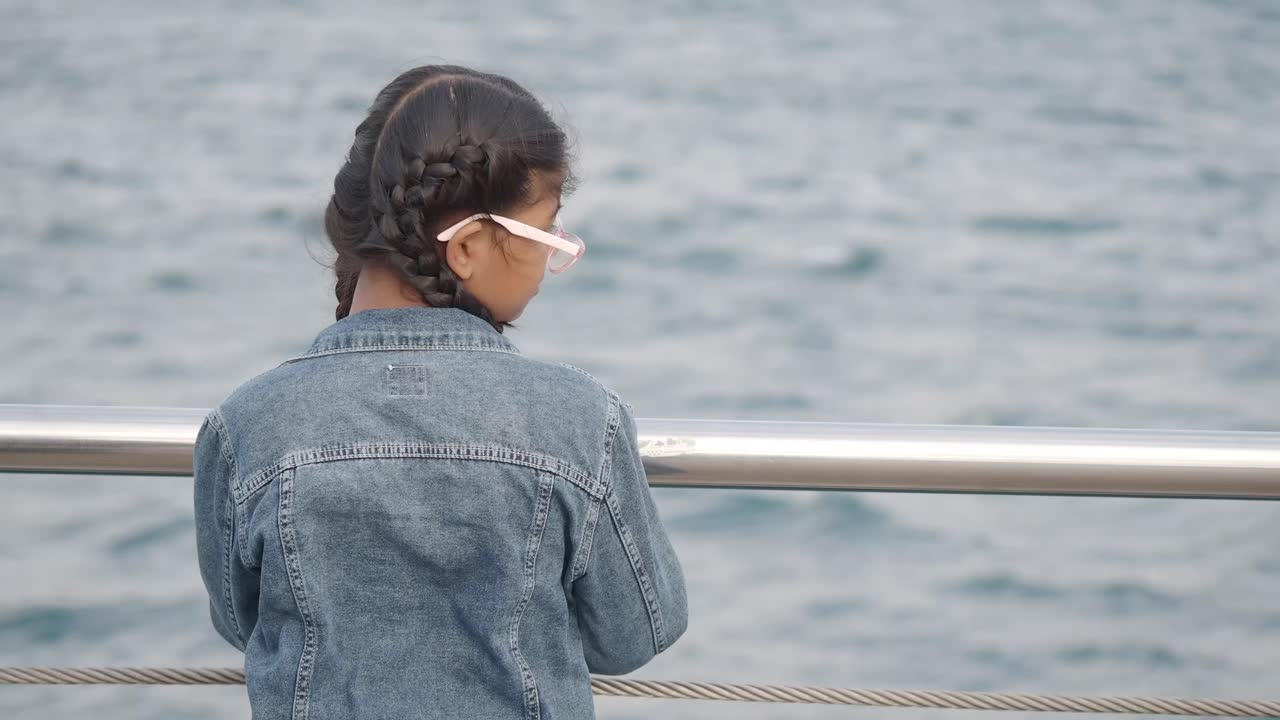 Mädchen mit Zöpfen, die auf den Ozean hinausschaut