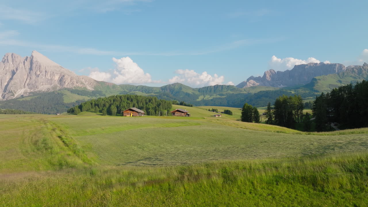 Drone viser Alpe di Siusi-landskap med åpne beitemarker og Dolomitt-topper midt på dagen