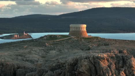 golden hour glow on defence tower in fornells bay, menorca spain