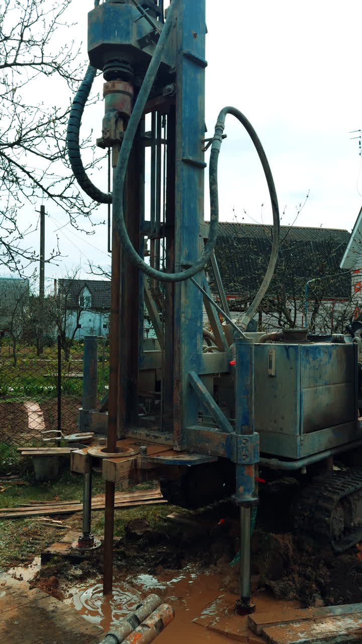 Drilling machine boring the well in the countryside. Equipment making a pore in the ground. Vertical video.