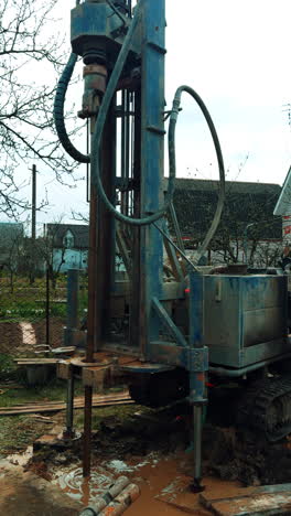drilling machine boring the well in the countryside. equipment making a pore in the ground. vertical video.