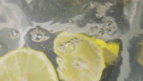 Fresh-lemon-pieces-gracefully-fall-in-water-creating-gentle-splash,-close-up