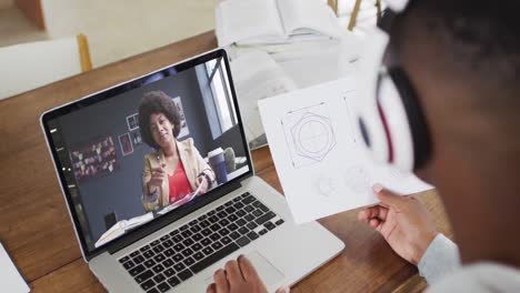 African-american-male-college-student-holding-notes-while-having-a-video-call-on-laptop-at-home