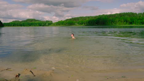 Cute-boy-with-swimwear-and-goggles-run-into-the-lake-and-swims