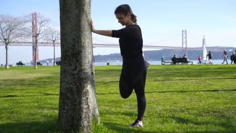 mujer joven atlética estirándose en el parque