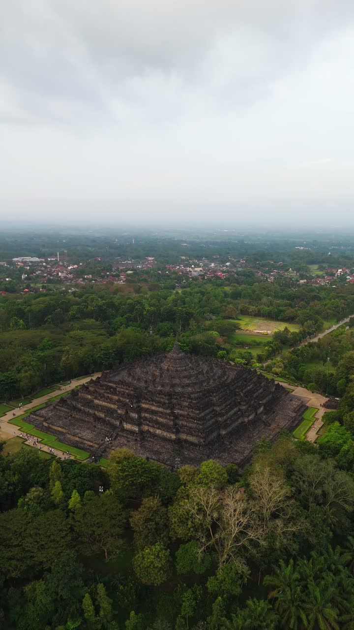 Ripresa aerea orbitale del tempio di Borobudur al tramonto dorato a Giava Centrale, dintorni lussureggianti, inquadratura verticale