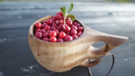 lingonberries in a wooden cup on table, close up panning shot